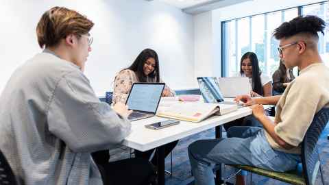 image of students sitting in front of laptops chatting
