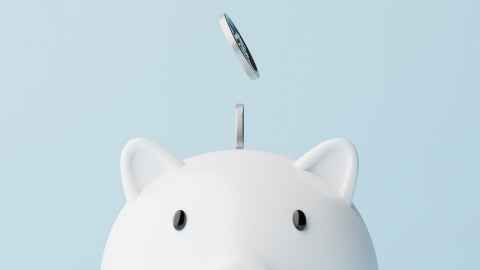 Coing dropping into a white piggy bank