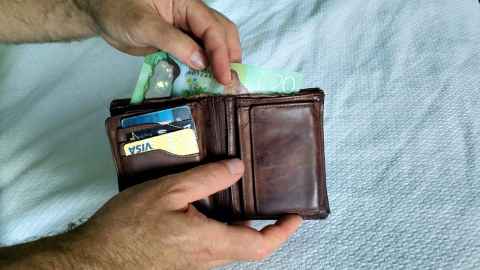 someone taking money out of a wallet filled with cards