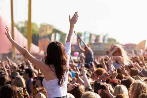 woman at music festival a crowd with hands in the air