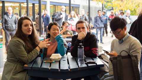Four students sitting around a table in the quad.