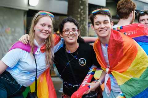 Three students posing for the camera at the Pride March