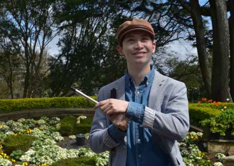 William stands with his cane and his penny whistle in Albert Park
