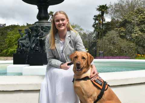 Sophie sits with her assistance dog Frankie, in front of the Albert park fountain 