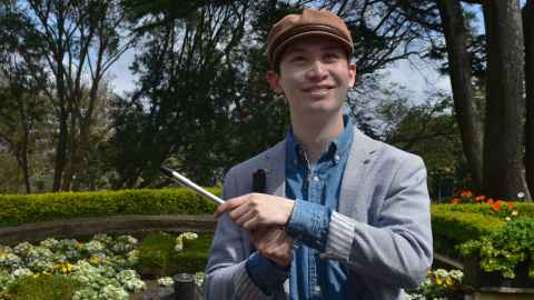 William stands with his cane and his penny whistle in Albert Park