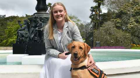 Sophie sits with her assistance dog Frankie, in front of the Albert park fountain 