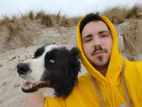 Kaden sits on the beach with his dog