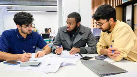 Three students studying together at a table.