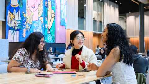 Trio of international students having a happy chat on a high table