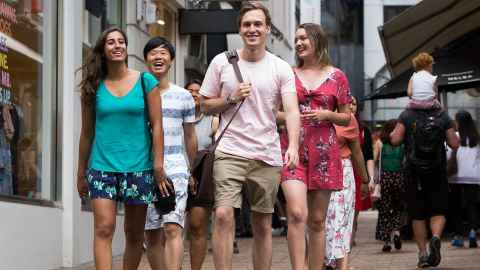 Group of smiling students walking on a city lane