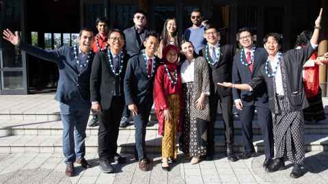 Students in formal and traditional dress celebrating the completion of their degrees