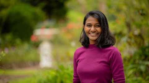 Smiling woman standing outdoors with trees in the background