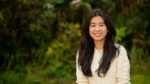 Smiling woman standing outdoors in front of a garden area