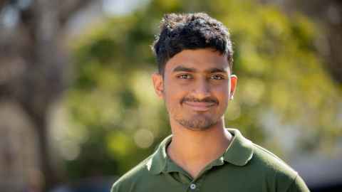 Smiling man standing outdoors with greenery in the background
