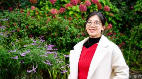 Woman standing in front of pink hydrangeas amongst the greenery