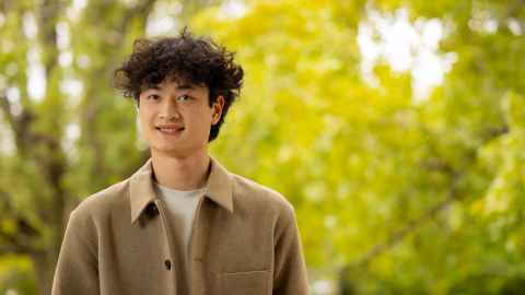 Smiling man standing outdoors with trees in the background