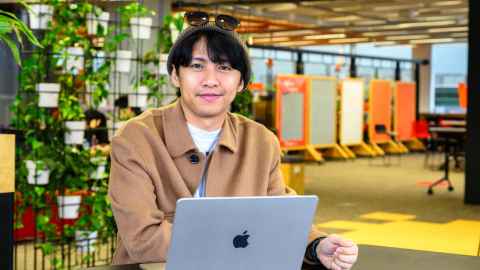 Man slightly smiling sitting at a laptop