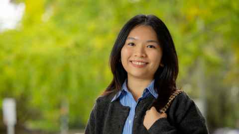 Smiling woman standing outdoors with trees in the background