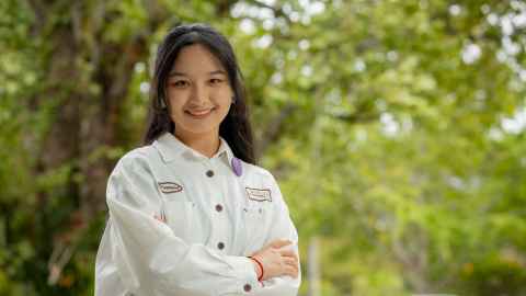 Smiling woman standing outdoors with trees in the background