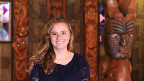 Smiling woman standing in front of taonga