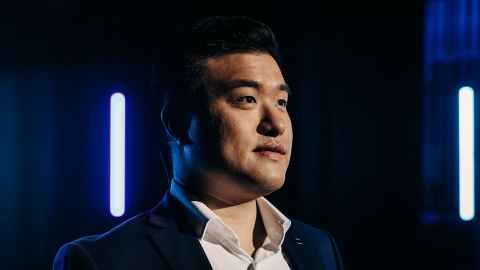 Young man looking into the distance, illuminated by stage lighting.