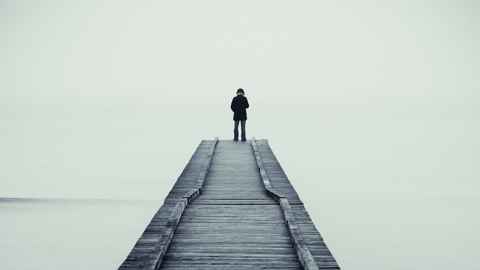 A person standing at the end of a long jetty.