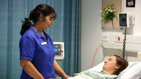 A nurse standing beside a patient in a hospital bed.