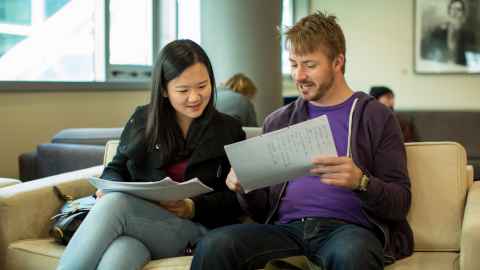 A young man showing a young woman next to him a piece of paper.