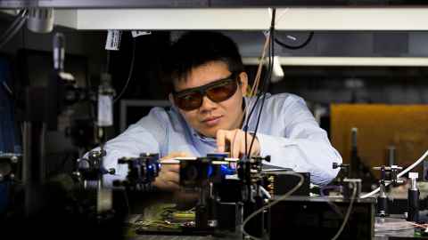A young man in dark glasses operating a machine.