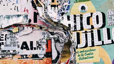 Layers of partially ripped posters on a wall.
