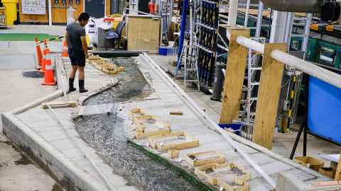 Water flowing through a channel cut in concrete, inside an Engineering lab.