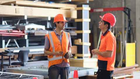 Two men in high-vis and hard hats on a building site.