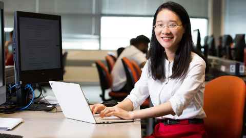 A woman at a desk, working on a laptop.