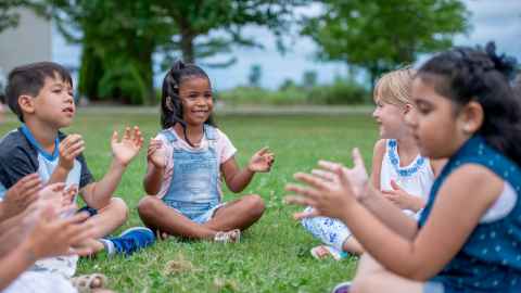 Children sitting in a circle, clapping their hands.