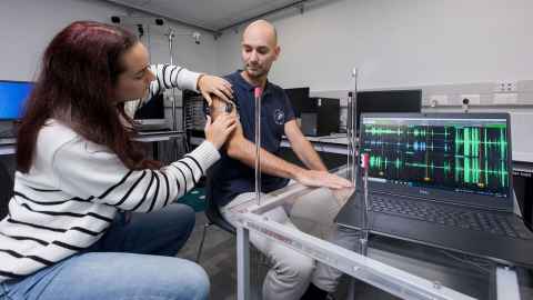 A woman attaching a monitoring device to a man's arm.