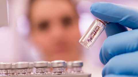 A person handling glass vials in a lab.
