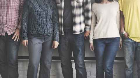 Men and women wearing jeans and t-shirts, photographed from the neck down.