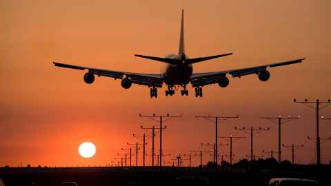 A plane landing as the sun goes down.