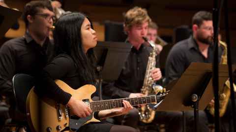 People playing instruments including guitar and saxophone.