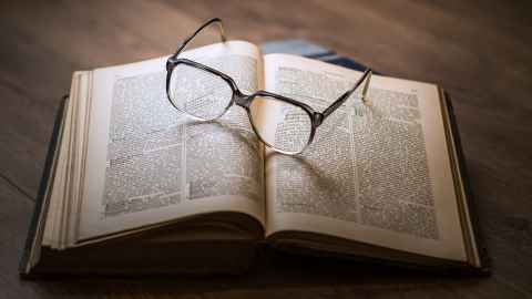 A pair of glasses lying on an open book.