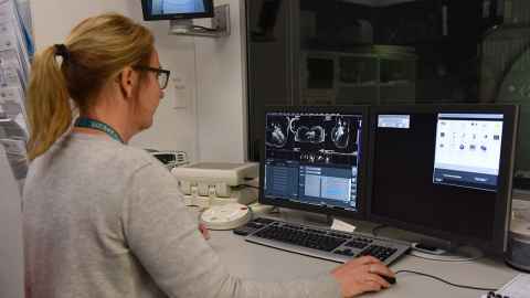 A woman at a computer with images from an MRI on the screen.