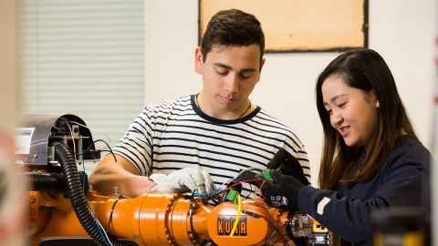Two people working on a mechanical device.