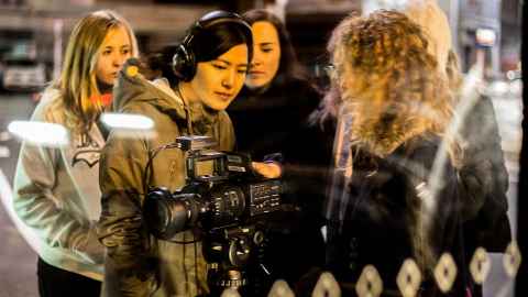 A group of young women standing around a camera.