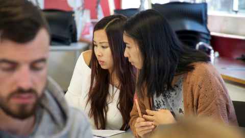 Three students - two young women looking at something we can't see, and a young man.