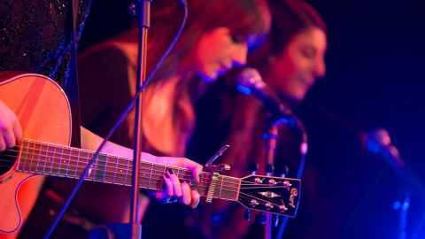People on a stage with microphones and a guitar.