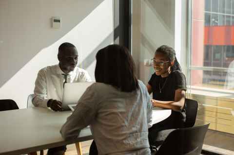 three employees having a discussion at a table