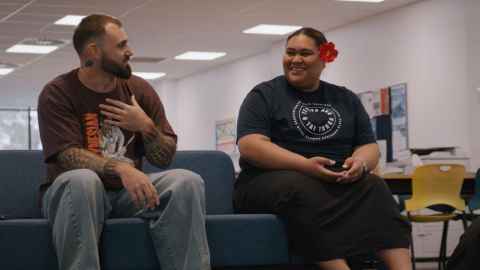Kereru cartoon bird perched on a tree branch overlooking the university of auckland campus