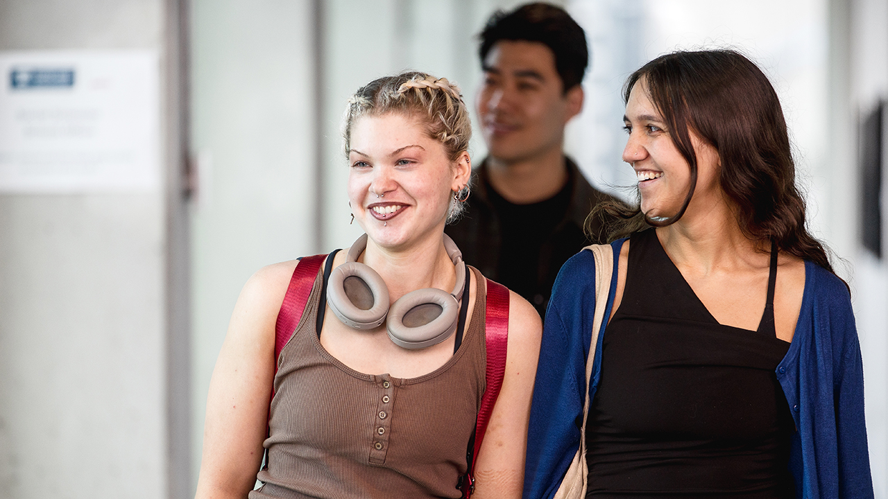 Three smiling students walking together.