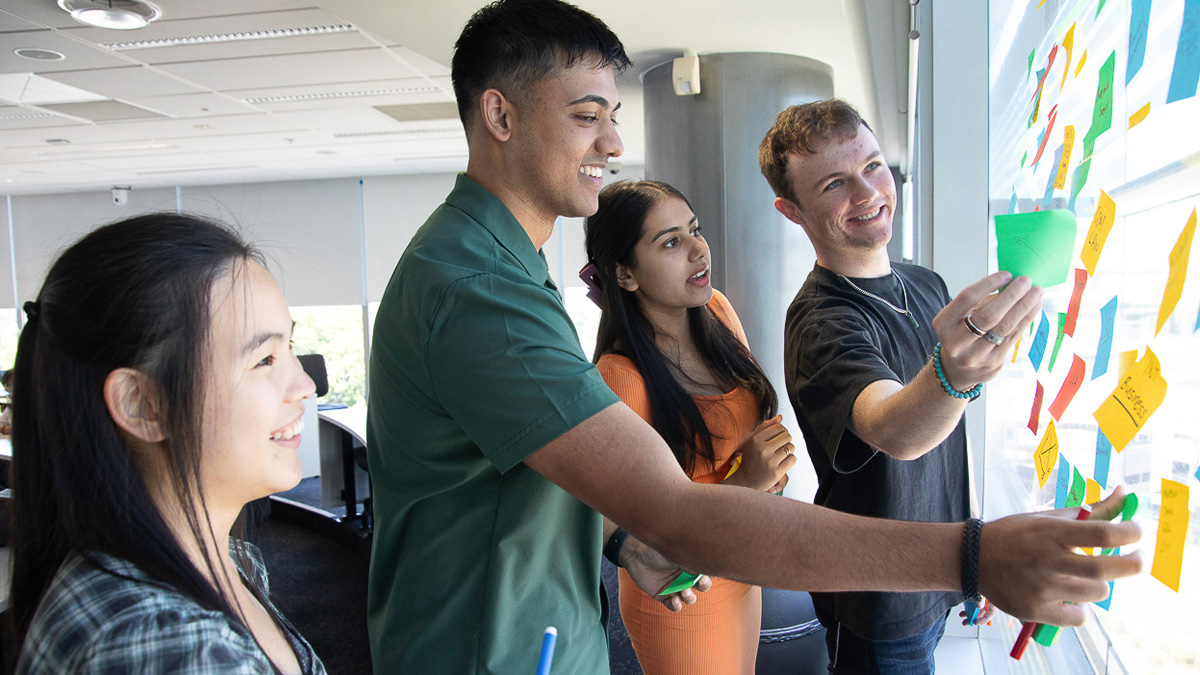 Group of students planning at a board with post-it notes.