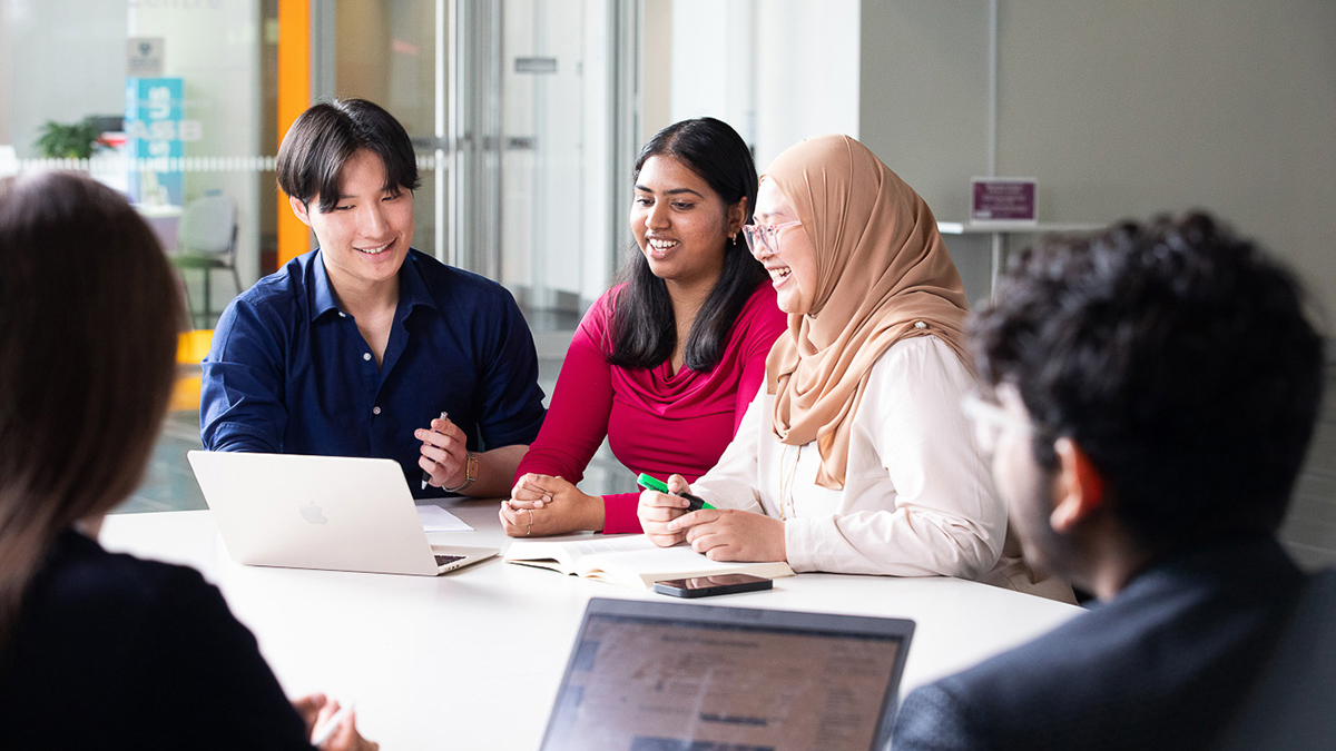 Group of happy students at a desk working together.